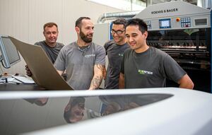 Four technicians talk shop on a new production machine.